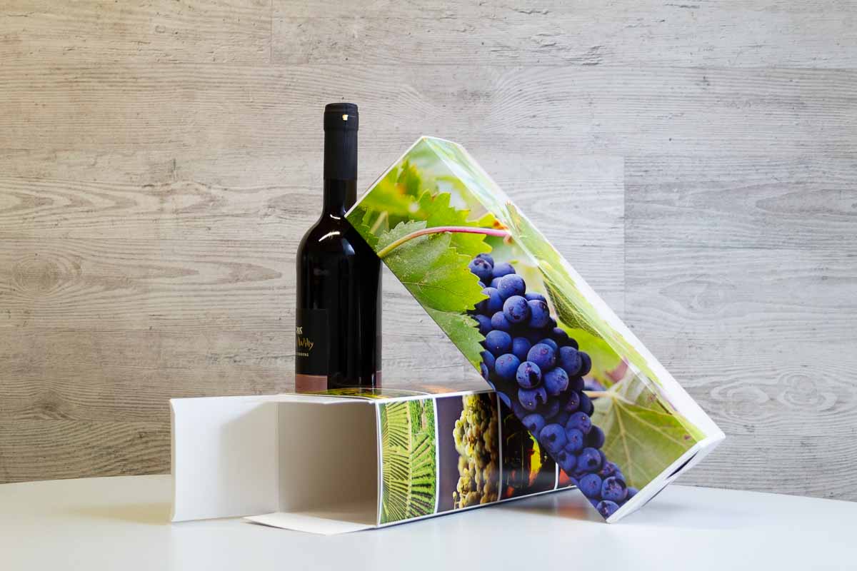 Individuell bedruckte Weinkartons Individuell bedruckter Weinkarton lehnt an einer Weinflasche.